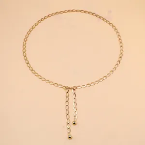 Detail van gouden metalen tailketting met holle ovale schakels en kralenkwastjes
