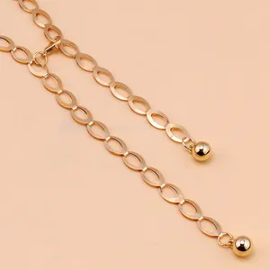 Detail van gouden metalen tailleketting met ovale schakels en ronde bolvormige hanger