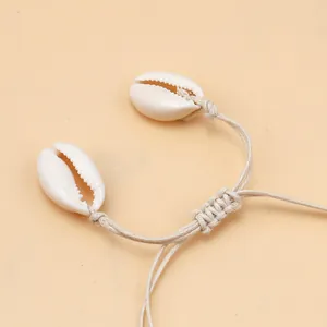 Close-up of hand-woven shell necklace with natural cowrie shells and adjustable beige cord