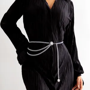 Detail of multi-layered silver alloy waist chain with floral buckle on a black dress