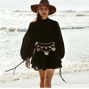Detail of multi-layered gold butterfly waist chain styled on a black lace beach dress