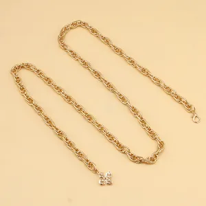 Detail of gold chain belt with twist links and sparkling clover rhinestone pendant
