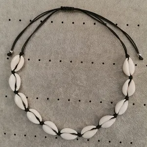 Detail of natural white cowrie shell necklace with adjustable black cord and silver beads
