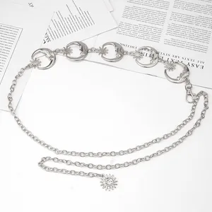 Détail d'une chaîne de taille argentée avec lune, étoile et pendentif soleil sur magazine