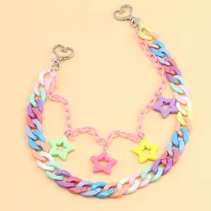 Macro detail of acrylic macaron star pendants and silver heart clasps on a stylish pant chain