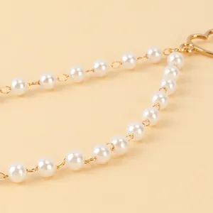 Detail von Kunstperlen und Goldkette mit Herzanhänger für elegante Lagen-Taillenkette
