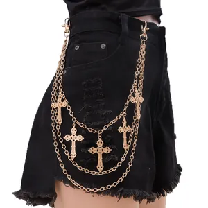Detail view of gothic multi-layer gold cross pendant chain on black denim shorts