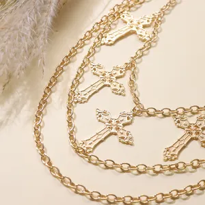 Detail of layered gold metal waist chain featuring ornate vintage cross pendants