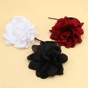 Detailed view of layered fabric flower chokers in white, burgundy, and black satin colors