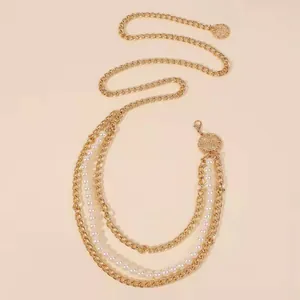 Détail d'une chaîne de taille dorée à plusieurs rangs avec perles et pendentif rond