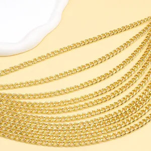 Makroaufnahme von mehrlagigen goldenen Metallketten auf beige-farbenem Hintergrund