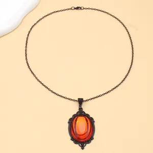 Detail of gothic vintage pendant featuring an oval orange quartz crystal in black alloy frame