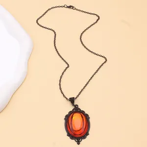 Detail of gothic necklace featuring oval orange crystal in a carved black metal frame
