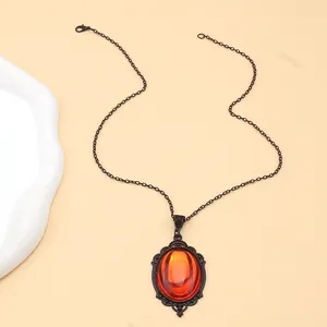 Close-up of gothic orange crystal pendant with vintage black metal filigree detailing