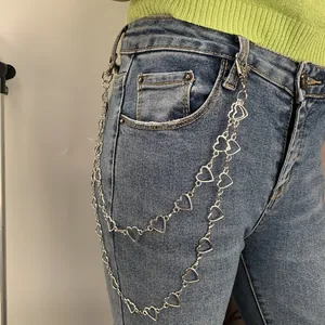 Detail view of double-layered silver heart chain belt on denim jeans for punk style