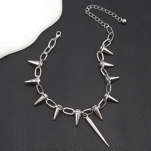 Detalle de collar punk con pinchos metálicos y flecos sobre fondo de cuero negro texturizado
