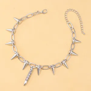 Detalle de gargantilla punk plateada con pinchos y colgante de bala con calavera