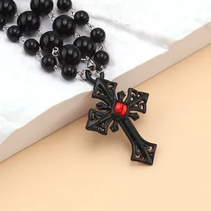 Détail d'un collier gothique perlé avec croix noire ornée et pierre gemme rouge