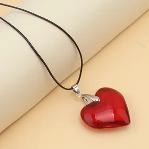 Macro view of a 3D translucent red heart glass pendant on a minimalist black rope cord