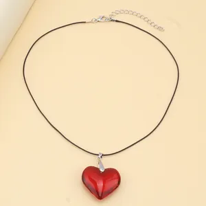 Detail of red glass heart pendant with black cord strap and silver lobster clasp closure