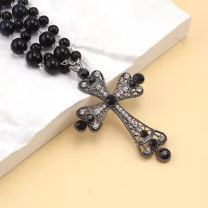 Gros plan du collier gothique à perles noires avec un grand pendentif croix strassé