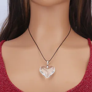 Minimalist heart-shaped glass pendant necklace with black cord shown on model
