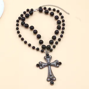 Collier de perles noires gothiques avec un grand pendentif croix orné de strass sur papier