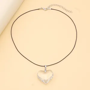 Detail shot of a minimalist heart-shaped glass pendant with adjustable black cord strap