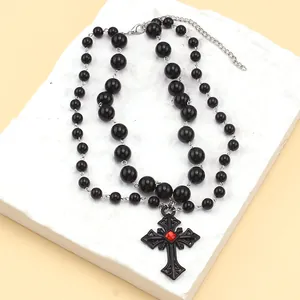 Détail du collier gothique à perles noires avec un pendentif croix serti d'une gemme rouge