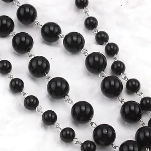 Détail de perles noires polies et d'anneaux en métal argenté sur un collier punk