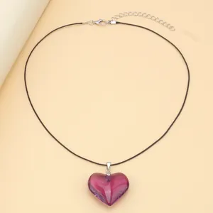 Detail view of purple glass heart pendant with black cord and adjustable metal clasp