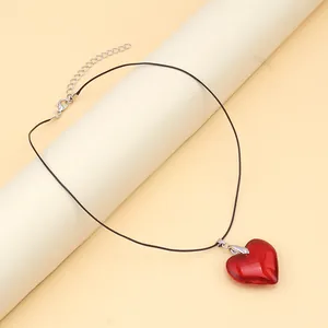 Macro detail of a red glass heart pendant necklace with adjustable black wax cord strap
