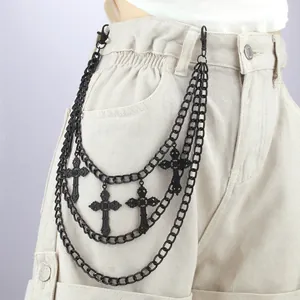 Detail of black multilayer punk waist chain with ornate cross charms on beige cargo shorts