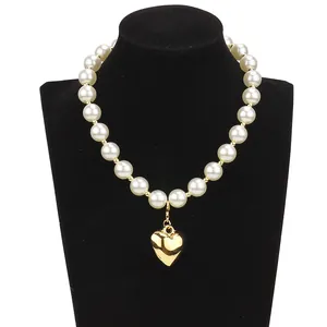 Double layered pearl necklace with polished gold heart pendant on jewelry display stand