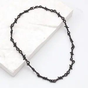 Detalle de collar punk negro mate estilo alambre de espino sobre podio de mármol
