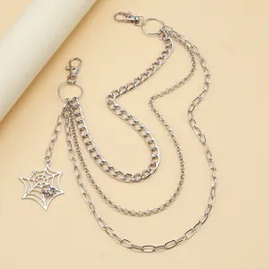 Macro detail of silver layered punk pant chain featuring a metallic spider web pendant