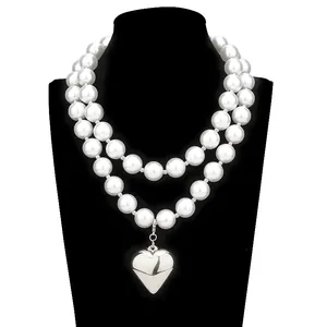 Double-layered pearl necklace featuring a large polished heart pendant on a black bust