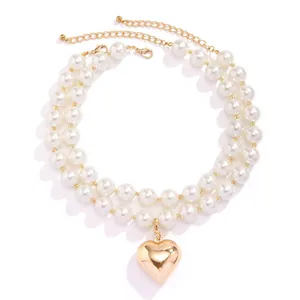 Double-layer pearl necklace with a polished gold heart pendant on white background