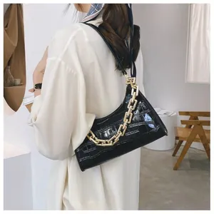 Detail of black faux crocodile skin shoulder bag with chunky gold chain strap