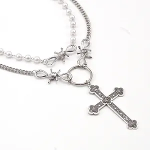 Close-up of double-layer necklace with pearl beads, thorns, and engraved cross pendant