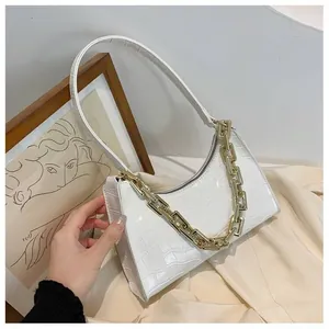 Detail of white crocodile pattern shoulder bag with chunky gold chain strap and zipper