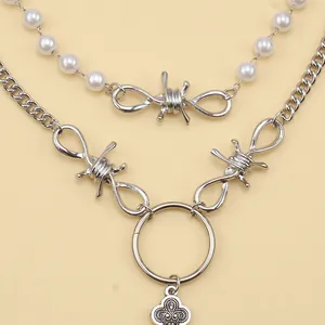 Detail of layered necklace featuring white pearls, silver mesh cross and floral pendant