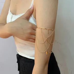 Close-up of gold layered arm cuff with hanging fringe chains and rectangular charms