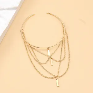 Detail of gold layered chain arm cuff featuring polished geometric bar pendants