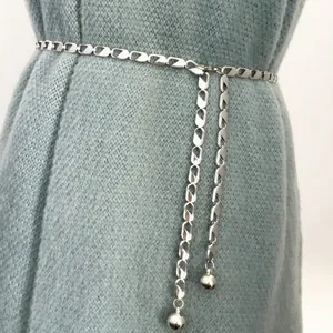 Minimalist silver metal chain belt with dangling polished ball pendants on a blue dress