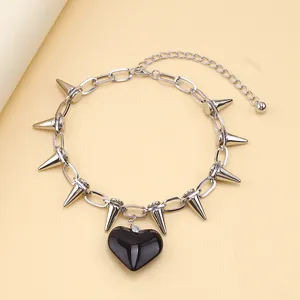 Macro detail of silver punk choker with black heart pendant and sharp metal spikes