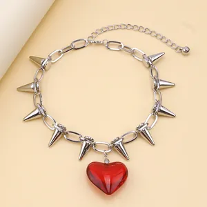 Macro view of silver spike chain necklace with a translucent red heart pendant