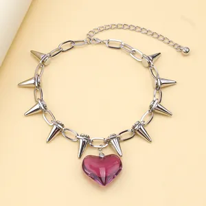 Macro detail of punk choker featuring silver metal spikes and a translucent red heart charm
