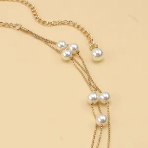 Detailed close-up of multi-layer gold chain belt featuring elegant white faux pearls