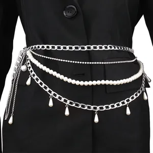 Layered pearl body chain with silver Cuban links and drop pendants over a black suit